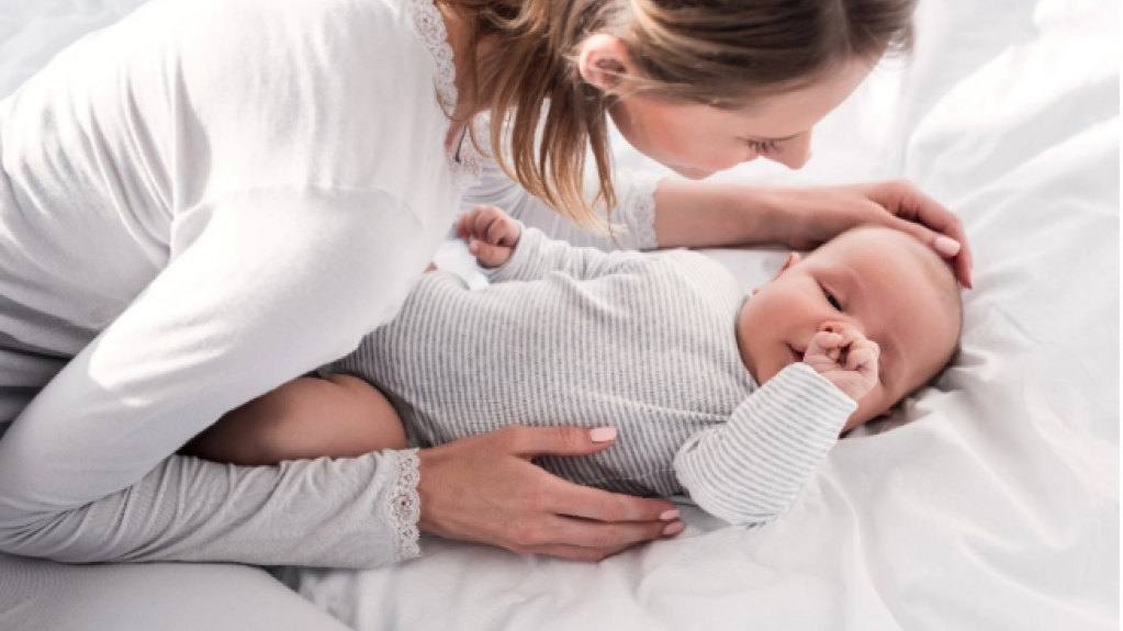 Mutter kuschelt nach der Geburt mit Baby im Bett